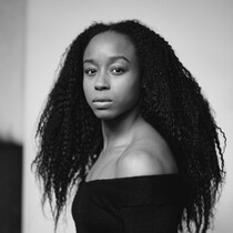Black and white image of a woman with a black strapless top and long hair.
