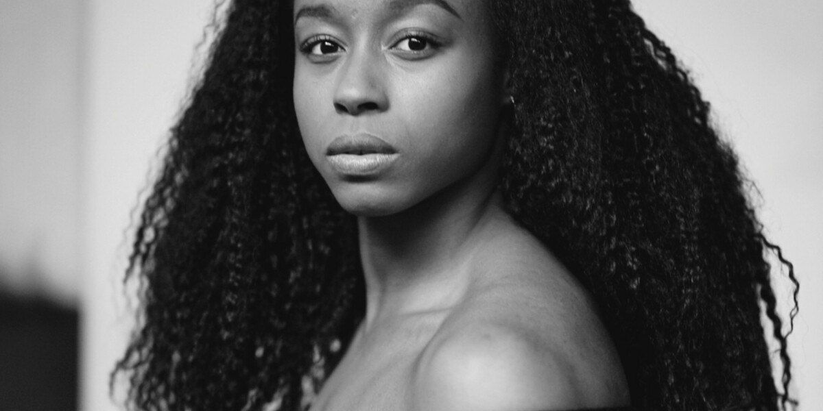 Black and white image of a woman with a black strapless top and long hair.