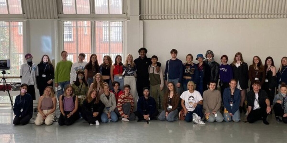 This is an image of LCDS BA1 students from 2021. A line of dancers sit down across the image. Another line of dancers stand up behind the ones sitting down.
