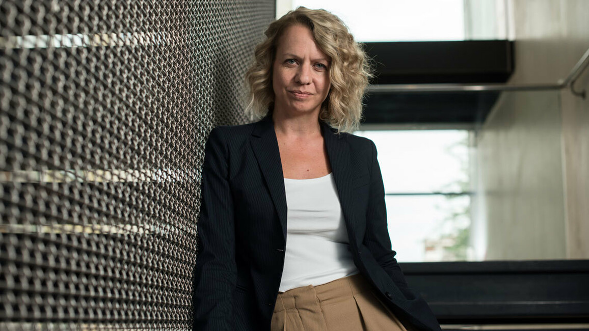 Clare Connor, Chief Executive of The Place is standing in a staircase wearing a white t-shirt and a blazer