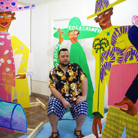 Image of Jose Campos / Studio Lenca sitting in the middle of the frame. Their artwork is surrounding them.