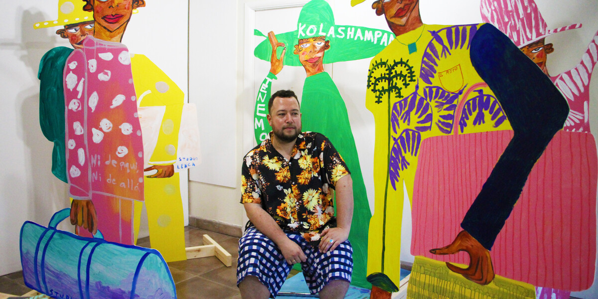 Image of Jose Campos / Studio Lenca sitting in the middle of the frame. Their artwork is surrounding them.