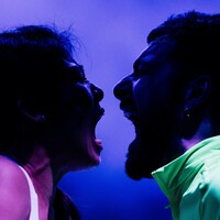 A woman and a man shouting into each others' mouths.