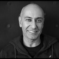 Image of Farooq Chaudhry. This image is black and white. Farooq smiles into the camera and wears a dark tracktop.