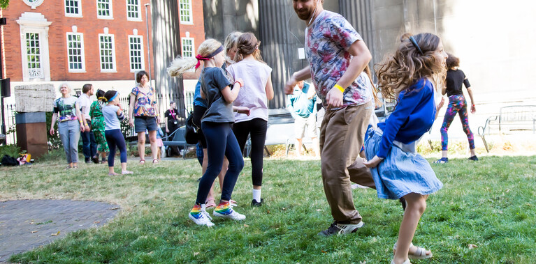 A mixed group of people of different ages outside moving around the space