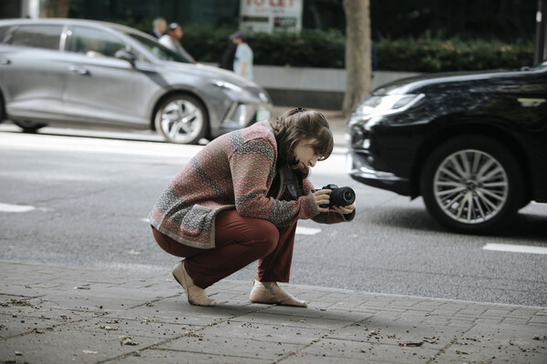 Student with a camera, kneeled down on the street to capture a shot