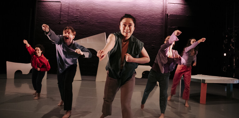 Five dancers energetically reach forward, their expressions animated and focused.