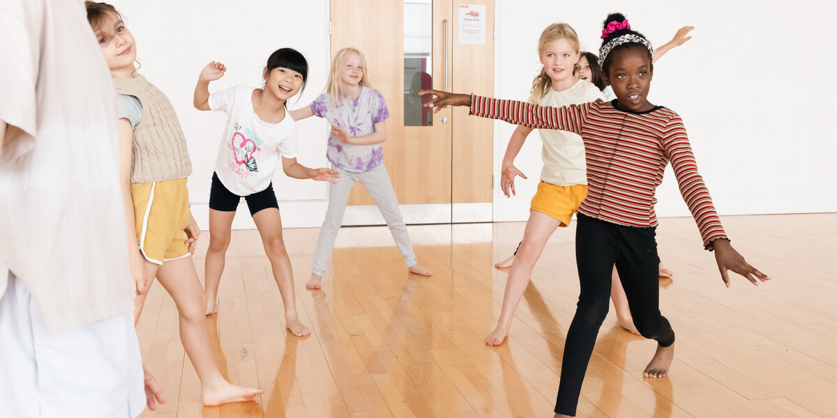 Children around 7 years old smiling and dancing.