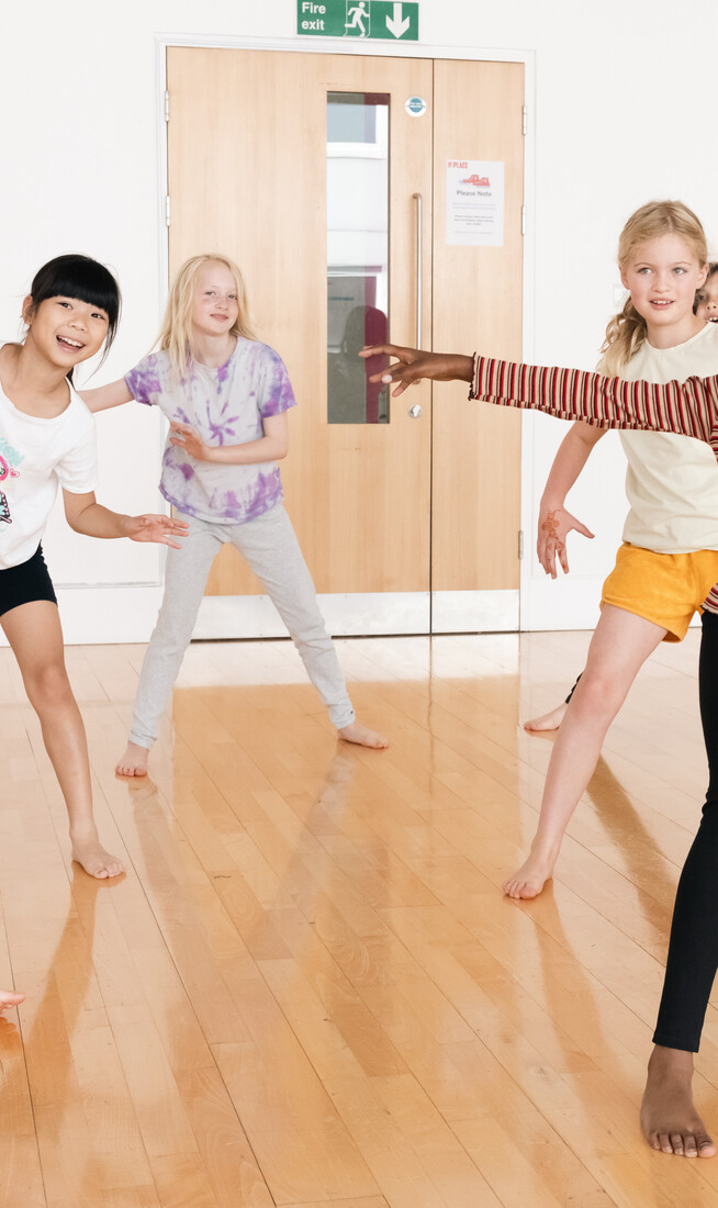 Children around 7 years old smiling and dancing.