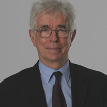 Image of Timothy Lankester. Timothy has grey silver hair and wearings silver glasses. He wears a dark suit and tie with a light blue shirt.